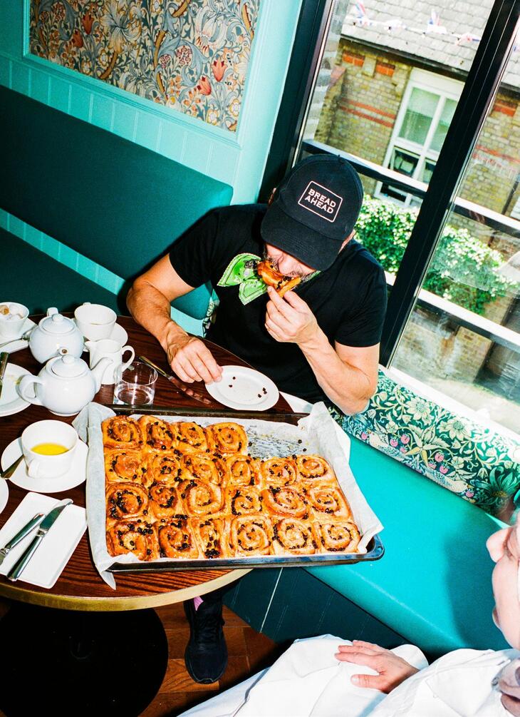 Someone eating a bun front a tray full of them