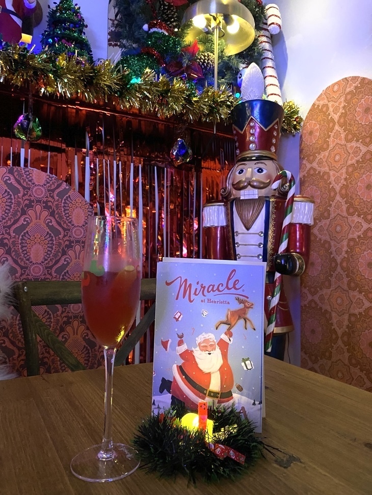 A glass of drink next to a nutcracker doll