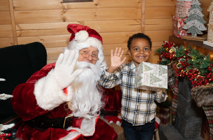 Best Santa's grottos meet Father Christmas London 2025 tickets: Santa and a young boy waving at the camera for a photo