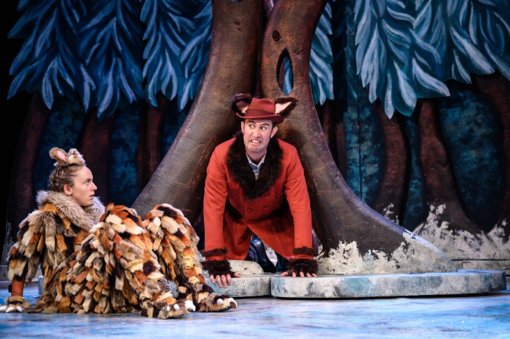 Family Christmas theatre shows 2025: one performer crawling out of a tree trunk towards the Gruffalo's Child sitting on the ground