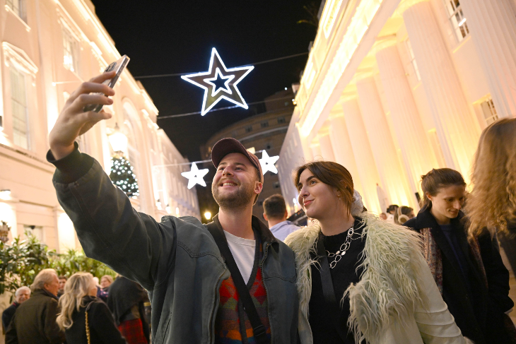 When are London Christmas lights 2025 switched on: a couple taking a selfie beneath star Christmas lights at Belgravia's switch on event