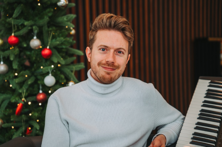 When are London's Christmas 2025 lights switched on: James B Partridge sitting at the piano with a Christmas tree in the background