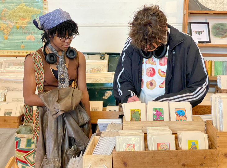 Things to do in London this weekend:  a man browsing a rack of prints on a stall while a woman watches