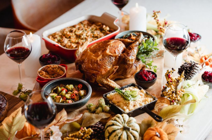 Thanksgiving 2025 in London: a thanksgiving feast including a whole roast turkey, many side dishes, and glasses of wine