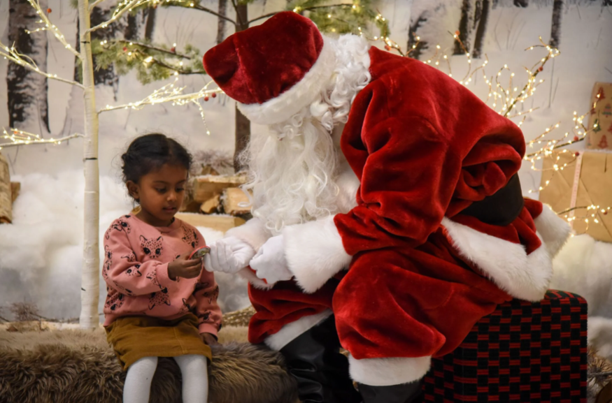 Best Santa's grottos meet Father Christmas London 2025 tickets: Santa passing a badge to a young girl