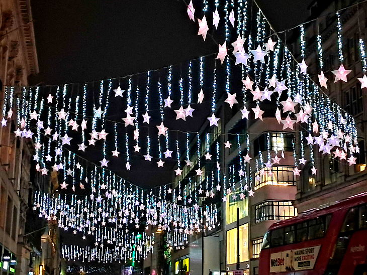 Best bus route to see Oxford Street Christmas lights 2025: star lights hanging over a bus on Oxford Street