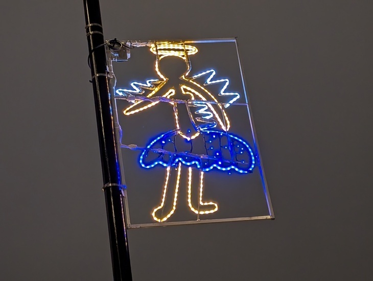 London Christmas light switch-on dates 2025: a child's illustration of an angel, made into a Christmas light and displayed on a lamp post