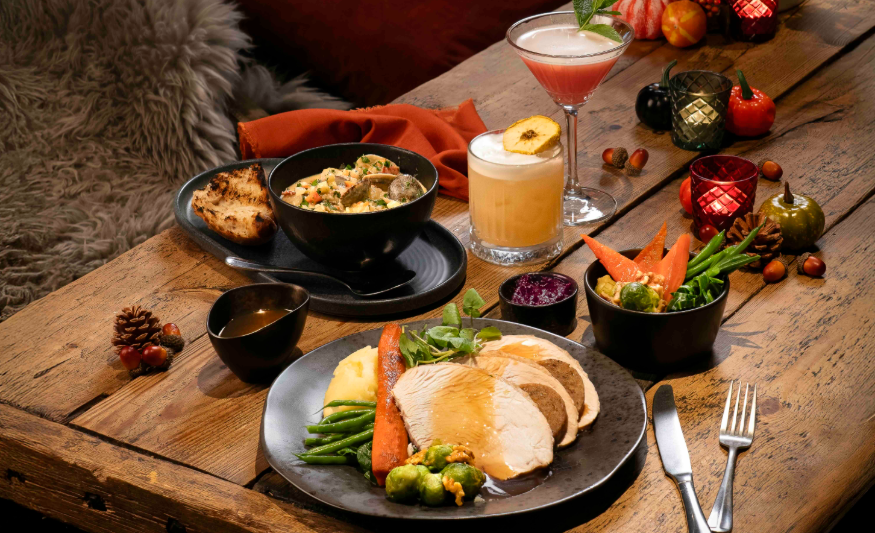 Thanksgiving 2025 in London: a table decorated for Thanksgiving, with a plate of turkey and vegetables, plus side dishes and cocktails