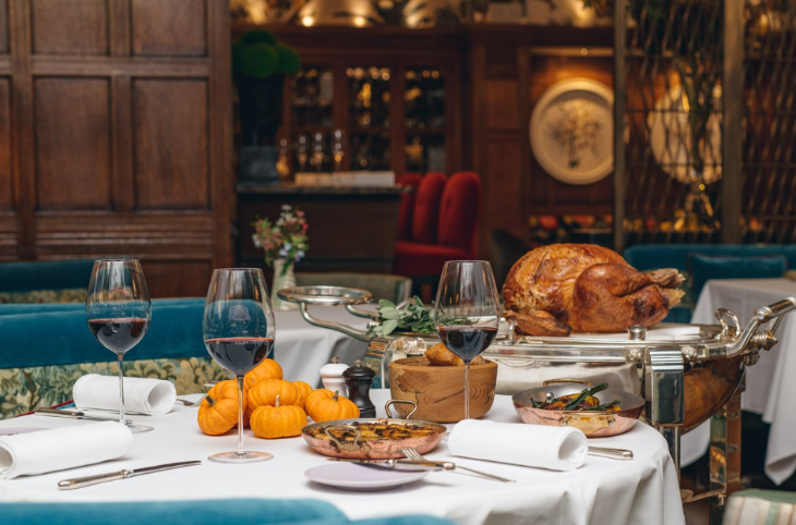 Thanksgiving 2025 in London: a roasted turkey, side dishes and wine on tables laid with white tablecloths