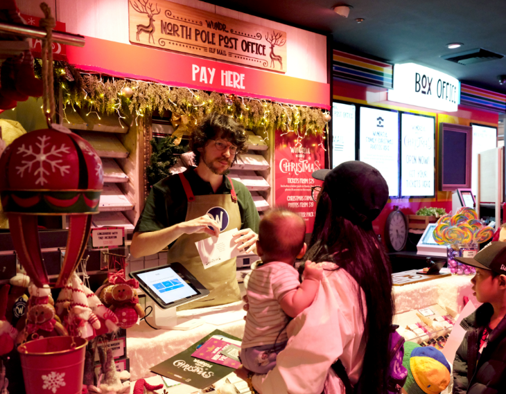 Things to do in London this weekend: a man serving a woman with a baby at the North Pole Post Office within the Wundrful World of Christmas