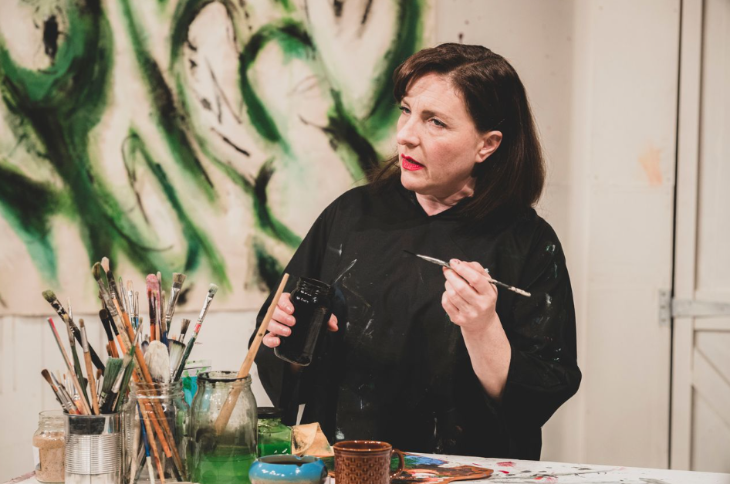Things to do today in London: a woman holding a paintbrush, surrounded by art materials