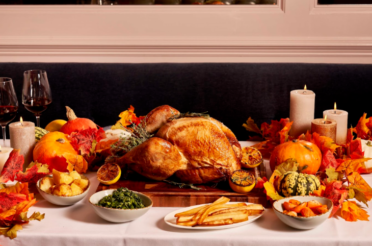 Thanksgiving 2025 in London: a roast turkey in the centre of a table which has been decorated with pumpkins, candles, and autumn leaves
