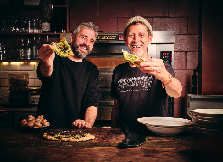 Two men with slices of pizza