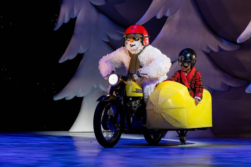 The Snowman on a bike with a child in a sidecar