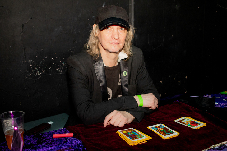 A tarot card reader sitting at a table