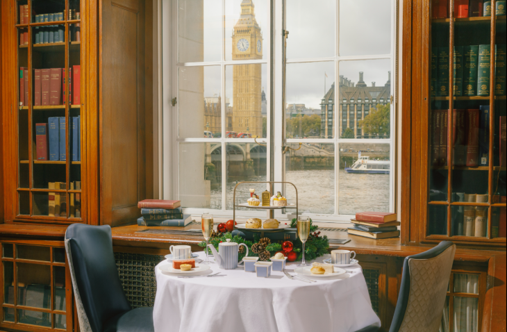 Best Christmas festive afternoon teas London 2025: an afternoon tea stand in front of a window with views across the river to the Houses of Parliament