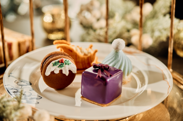 Best Christmas festive afternoon teas London 2025: pastries including a Christmas pudding macaron and a purple present on a plate