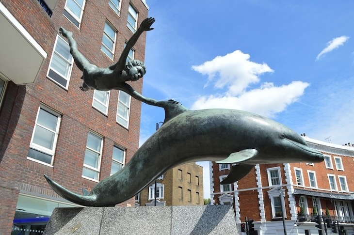 A boy riding a dolphin sculpture
