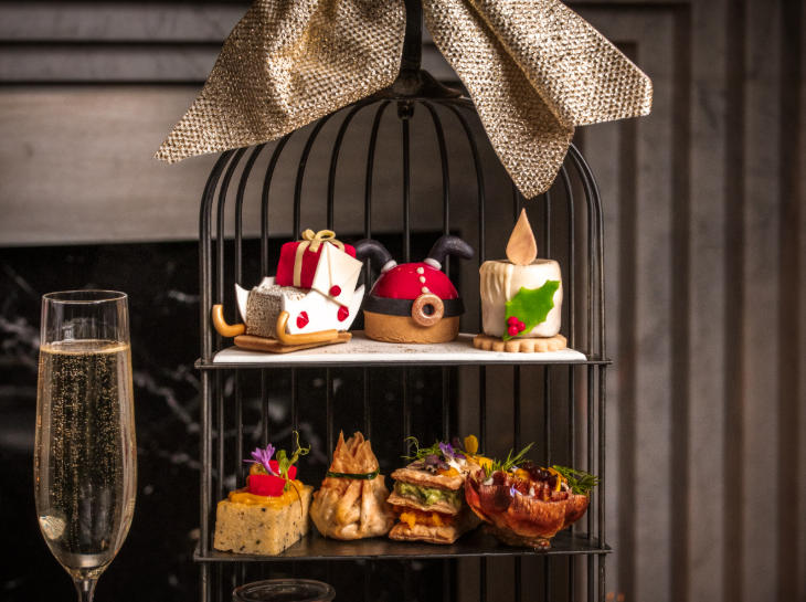 Best Christmas festive afternoon teas London 2025: Christmas pastries and savoury snacks on a tiered stand, alongside a glass of champagne