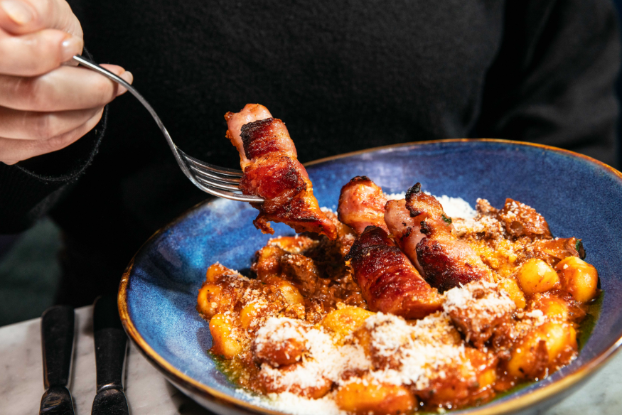 Free events in London: a person holding a fork, digging into a plate of pasta with pigs in blankets