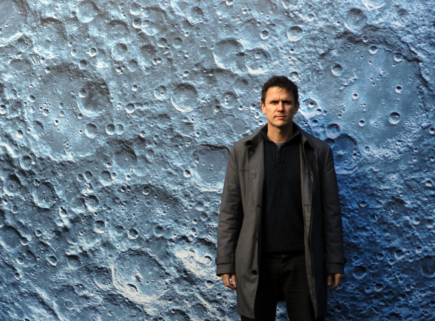 Luke Jerram standing in front of a replica of the surface of the Moon