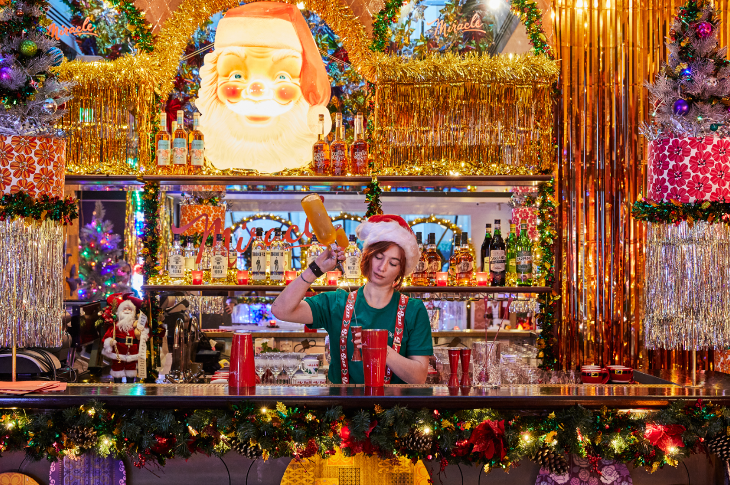 Christmas 2025 in London guide: a bartender dressed as an elf making drinks in a very Christmassy bar