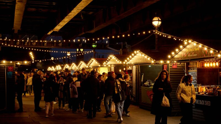 Christmas 2025 in London guide: people strolling past wooden chalets at a Christmas market