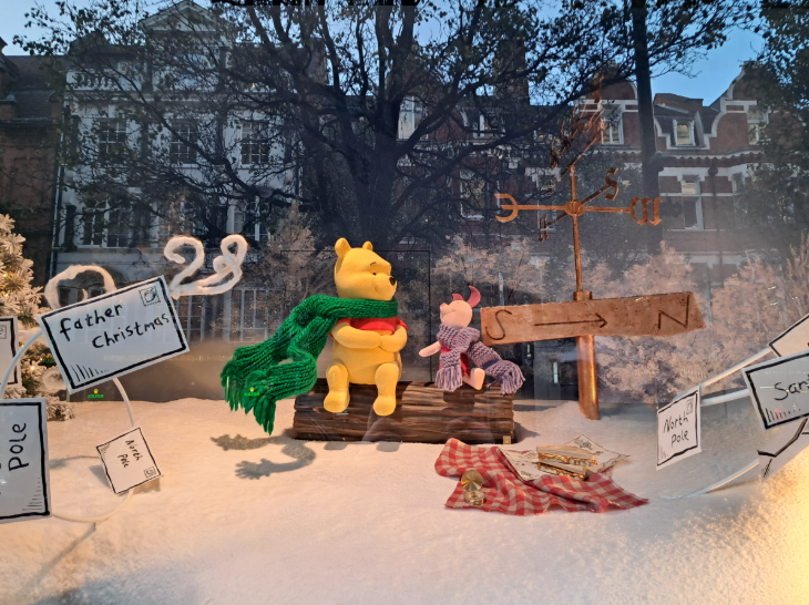 Self-guided Christmas lights walk London 2025:  Winnie the Pooh and Piglet sitting on a log in the Selfridges Christmas windows