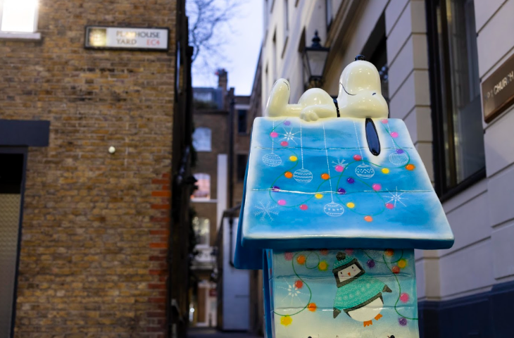 A sculpture of Snoopy on top of a kennel