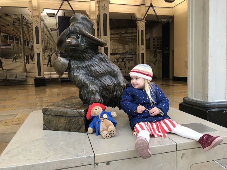 A young girl with a Paddington statue