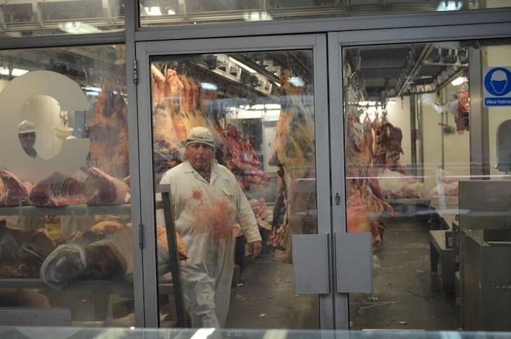 A butcher in stained overalls inside Smithfield meat market