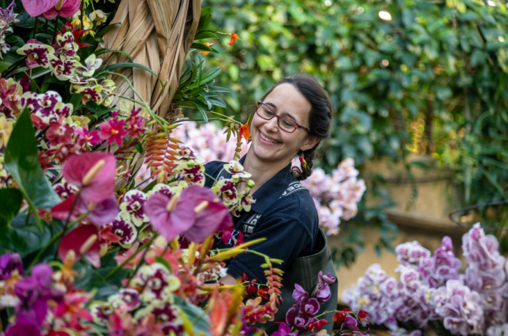 Things to do in London in winter 2026:  a woman smiling as she arranges an orchids display