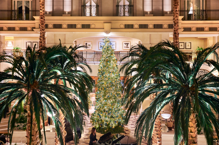 Things to do in London Christmas week: a palm tree and Christmas trees inside the atrium at Landmark London