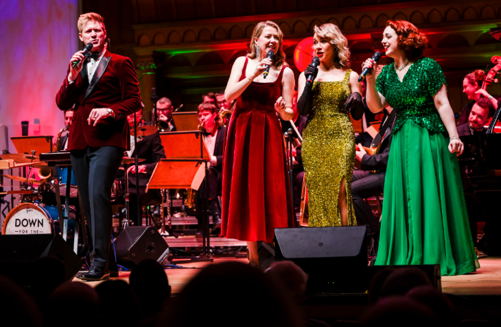 A male singer and three female singers performing on stage
