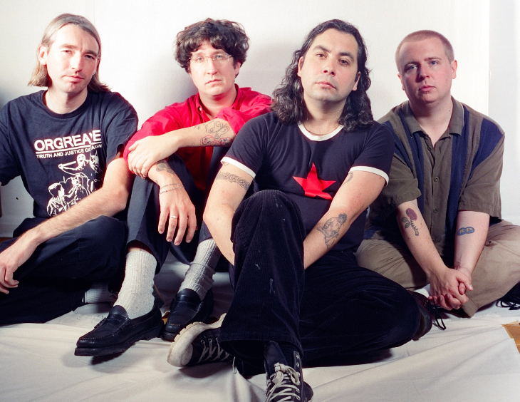 Four people sitting on the floor looking at the camera