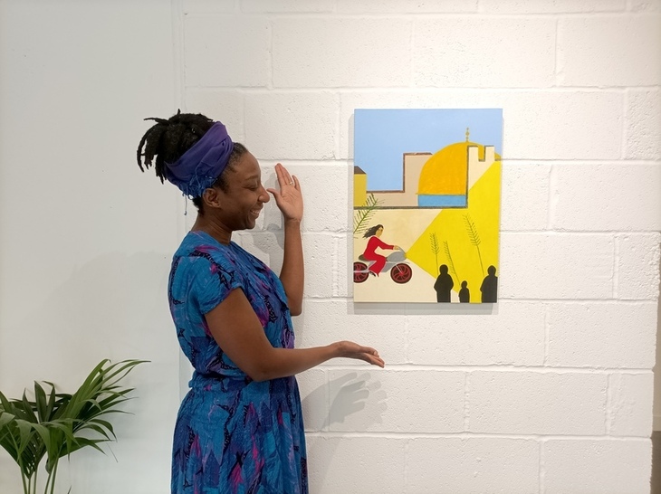 A woman showing off a painting on the wall