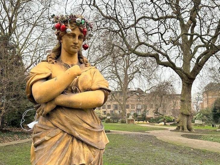 A yellow statue with Christmas baubles