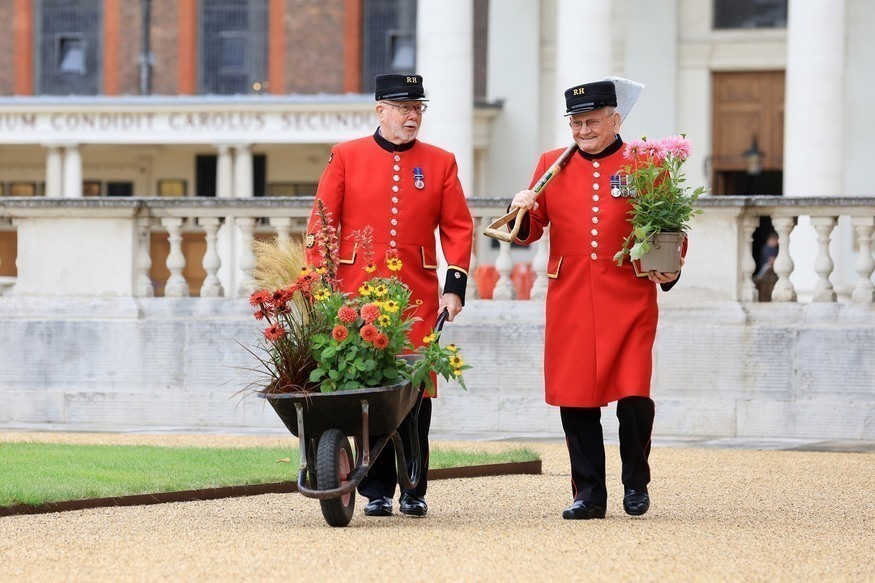 What's on in London in Spring 2026: Two Chelsea Pensioners in red uniforms pushing a wheelbarrow full of flowers