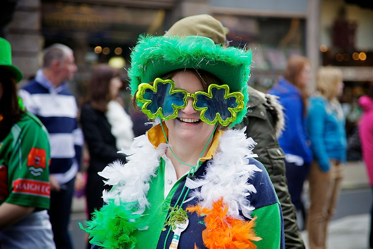 St Patrick's Day Parade London 2026: A women wearing shamrock glasses, green fluffy hat, and feather boa in the colours of the Irish flag at the London St Patrick's Day Parade