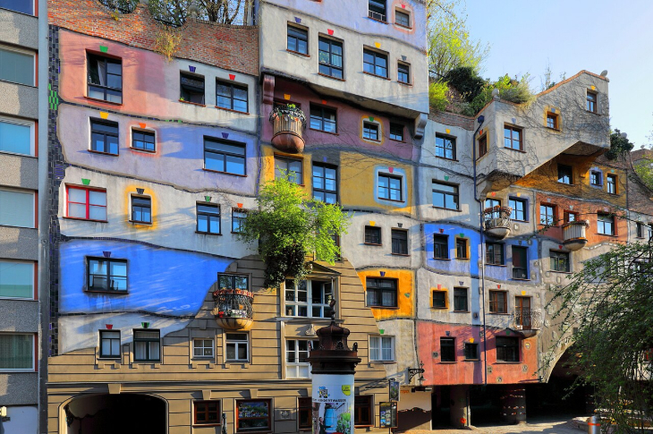 Tips for visiting Vienna: a building with irregular windows, painted in different colours, with plants growing out the side