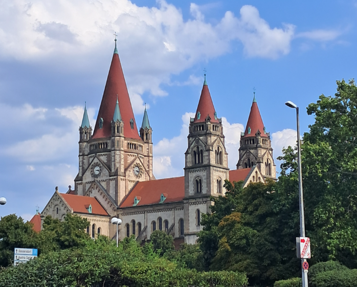 Best things to do in Vienna: a beautiful church building with three towers and a red roof