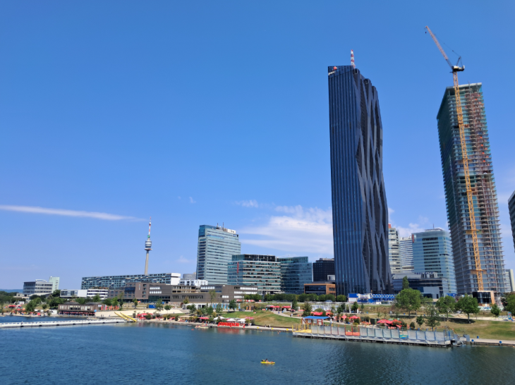 Tips for visiting Vienna:  two skysrcapers and several smaller glass buildings alongside the River Danube