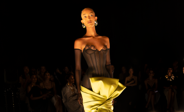 What's on in London in Spring 2026: a model wearing a dress consisting of a black corset, long black gloves, and a structured gold skirt