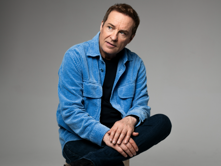 Things to do in London this weekend: Ardal O' Hanlon sitting with one leg crossed over the other, wearing a blue jacket