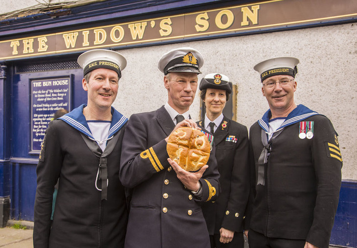 Naval officers holding a hot cross bun