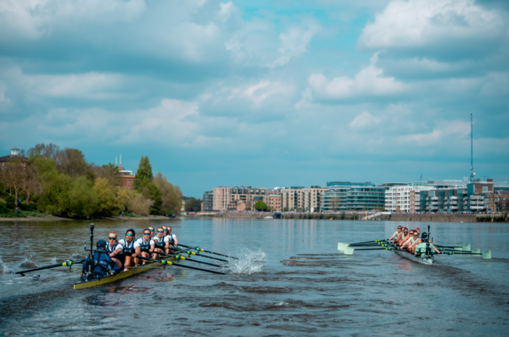 Two teams rowing alongside each other on the Thames