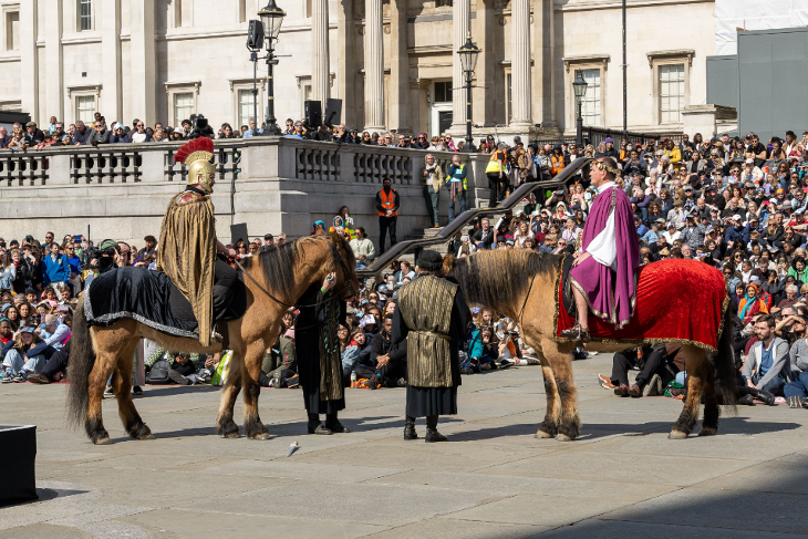 The Passion of Jesus in Trafalgar Square on Good Friday: Crowds sitting on the floor in Trafalgar Square watching two actors mounted on horses