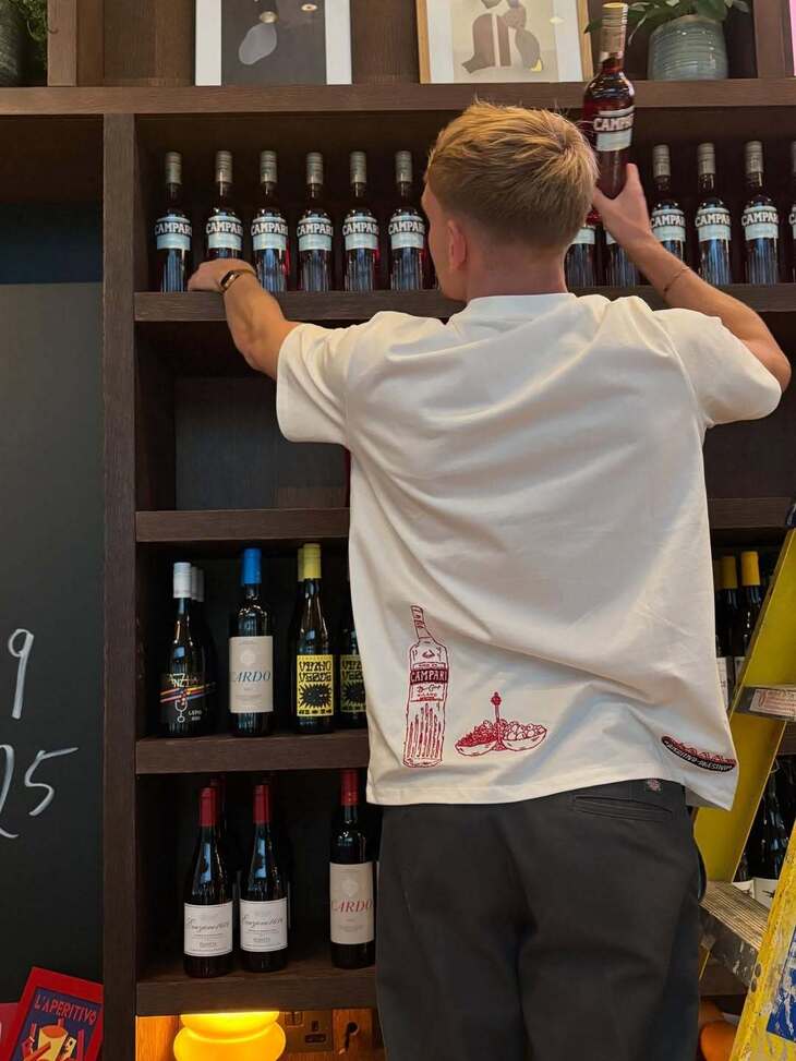 A person getting Campari bottles down from a shelf