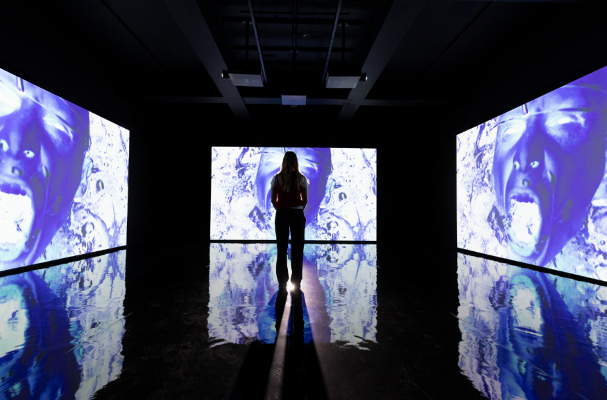Best events in London today: a person silhouetted in the centre of a room, surrounded by illuminated screens