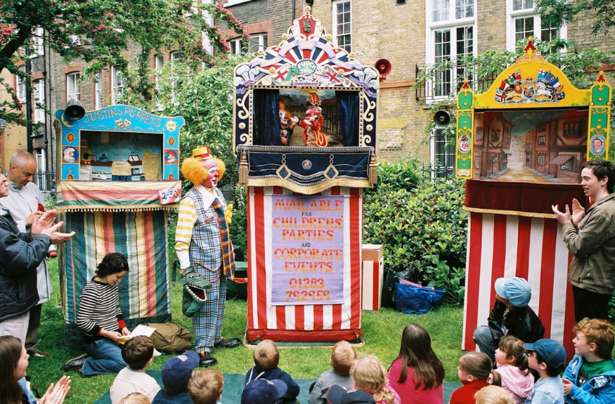 Covent Garden Puppet Festival: Children sitting on the grass watching a Punch & Judy show at the Covent Garden Puppet Festival